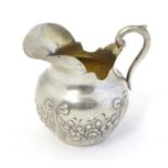 A small Continental silver cream jug with bow and swag decoration. Marked under 800 and with maker?s