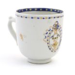 A Chinese export tea cup with hand painted decoration depicting an armorial crest with birds, with a