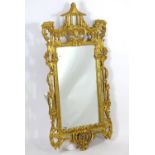 A carved giltwood pagoda mirror with stylised foliate carving, scrolled decorations and flanked by
