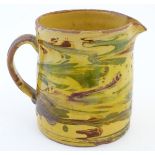 A 19thC studio pottery slipware jug with a yellow ground. Indistinct incised mark under. Approx. 5''