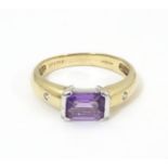 A 9ct gold amethyst and diamond ring, the central amethyst flanked by two diamonds . Ring size