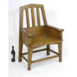An Arts and Crafts oak throne chair with a pointed, slatted backrest and a chamfered frame and