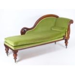 A late 19thC / early 20thC mahogany chaise longue with a scrolled show wood frame and raised on