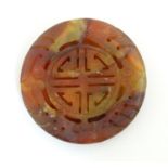 An Oriental hardstone roundel carving depicting stylised a dragon and scrolling foliage. Approx. 2