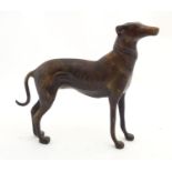 A cast brass model of a greyhound / long dog, with bronzed finish, standing 9" long, 8 1/8" tall