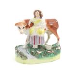 A Staffordshire model of a cow with a milkmaid on a naturalistic base. Approx. 6 1/2" high Please