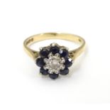 A 9ct gold ring set with central diamond bordered by 8 blue spinel in a daisy setting. Ring size