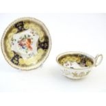 A hand painted tea cup and saucer with a blue ground, gilt highlights and central flower decoration.