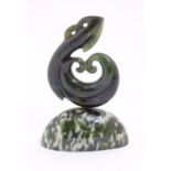 An Oriental nephrite / hardstone carving depicting a stylised scrolling beast on a hardstone base.