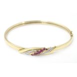 A 9ct gold bracelet of bangle form set with rubies and diamonds Please Note - we do not make