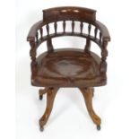 An early 20thC oak desk chair with a bowed backrest and turned spindle supports above a saddle