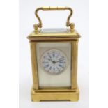 A large 20thC carriage clock of glit metal and bevelled glass construction, with a white enamel dial