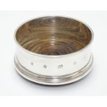 A silver coaster with turned wooden base. Hallmarked Birmingham 1987 maker Argyll Silver. 4"