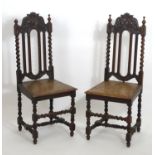 A pair of early 20thC oak side chairs with carved frames above barley twist supports and a floral