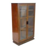 An early / mid 20thC Art Deco bookcase with a moulded top above two glazed panelled doors. 36 1/2"