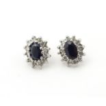 A pair of 9ct gold stud earrings set with central sapphire coloured spinel bordered by white stones.