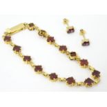 A 14ct gold bracelet set with 14 garnets together with matching stud earrings Please Note - we do