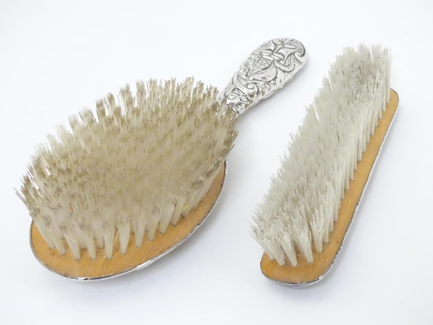 A silver handled brush together with a silver backed brush both with embossed decoration. Hallmarked