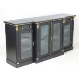 An ebonised breakfront sideboard with ormolu mounts and knob handles, egg and dart moulded trim