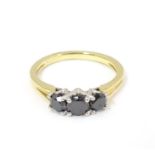 An 18ct gold ring set with trio of black diamonds. Ring size approx O Please Note - we do not make