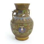 An Oriental cast vase of baluster form with twin animal head handles, the body with champleve enamel