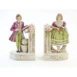 A pair of German porcelain figural bookends depicting a gentleman and a lady with flowers. Marked
