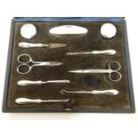A cased manicure set / necessaire containing silver mounted pots, nail buffer, file, tweezers,