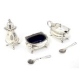 A silver three piece cruet set comprising salt, mustard and pepper pot, with blue glass liners and