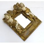 A contemporary wall mirror with gilt and cream decoration of cherubs flanking a bow, the whole 9 1/
