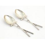 A pair of silver teaspoons, the handles formed as crossed golf clubs with golf ball spacers.