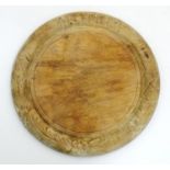 A Victorian carved sycamore bread board of circular form with flower and foliate detail. Approx.