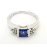 A 9ct white gold ring set with central sapphire flanked by diamonds. Ring size approx L 1/2 Please