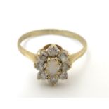 A 9ct gold ring set with opal like cabochon bordered by white stones. Ring size approx L Please Note