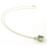 A 9ct gold pendant set with pale green spinel and diamonds on a 16" long 9ct gold chain. The pendant