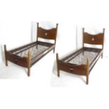A pair of early 20thC oak Arts & Crafts beds with original Heal's sprung bases. Having chamfered