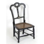 An early 20thC ebonised childs chair with mother of pearl decoration and a caned seat. 15" wide x