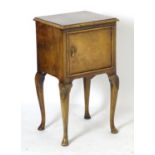An early 20thC walnut bedside cabinet with a moulded top above a single panelled door and Dutch drop