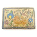 A 19thC rectangular Persian tile with hand painted decoration depicting a seated man playing a