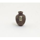 A Japanese ojime bead formed as a stylised vase with impressed detail and applied character mark