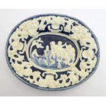 An Italian style charger of oval form with relief decoration depicting putti in a landscape with a