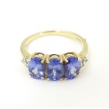 A 9ct gold ring set with three oval tanzanite flanked by three diamonds to shoulders. Ring size