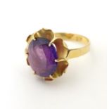 A gold ring marked '21k' set with oval facet cut purple coloured stone. Ring size approx K Please