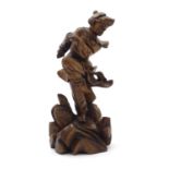 An Oriental carved wooden figure modelled as man on a rocky outcrop with foliate detail. Approx.