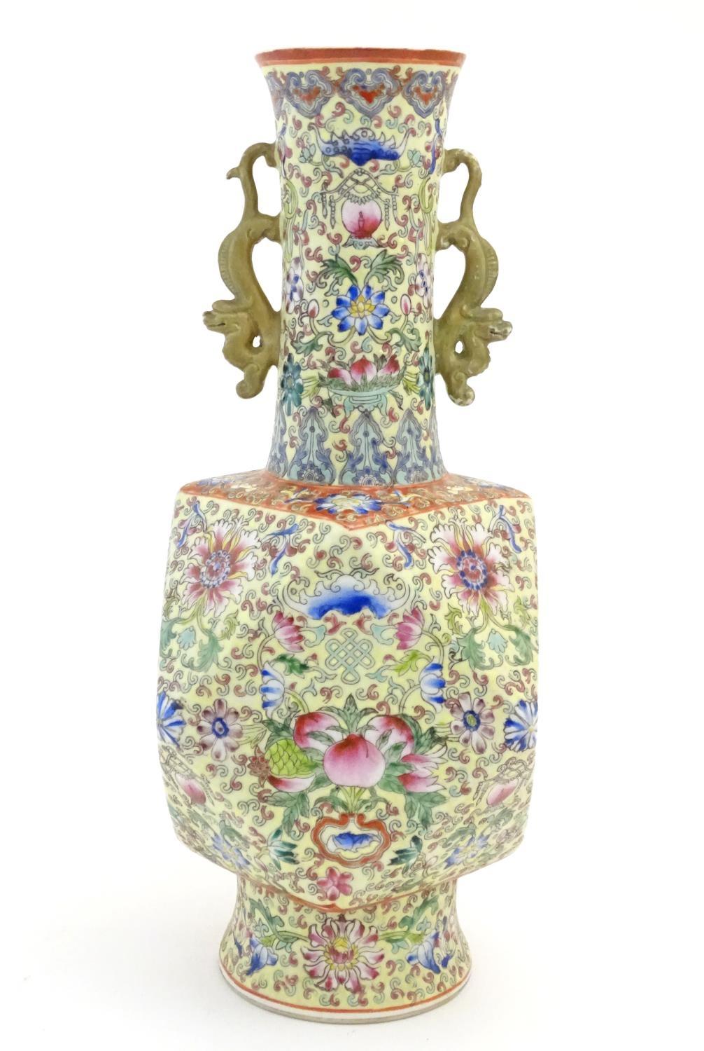 A Chinese famille jaune vase with twin handles modelled as stylised dragons, the body decorated with