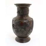 A Japanese cast vase of baluster form with panelled decoration in relief depicting birds among