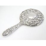 A silver handled mirror with embossed decoration, hallmarked Birmingham 1977, maker W. I. Broadway &