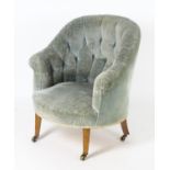 An early 20thC button back armchair with a shaped backrest and standing on tapering legs terminating