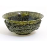 An Oriental dark mottled green soapstone bowl with carved stylised dragon and phoenix bird