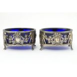 A pair of Continental silver salts with cherub, bow and swag decoration. With blue glass liners.