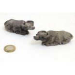 A pair of Oriental carved soapstone models of recumbent water buffalo. Incised marks under.